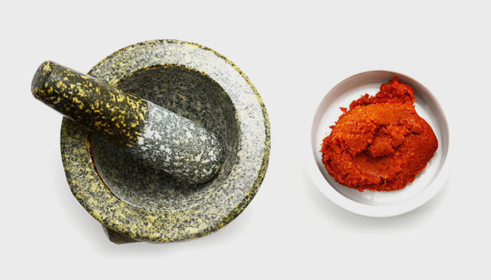 A mortar and pestle next to a bowl of food.